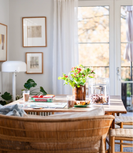 Ljus matplats med stolar, blombukett på bordet och stora glasdörrar som vetter mot en balkong.