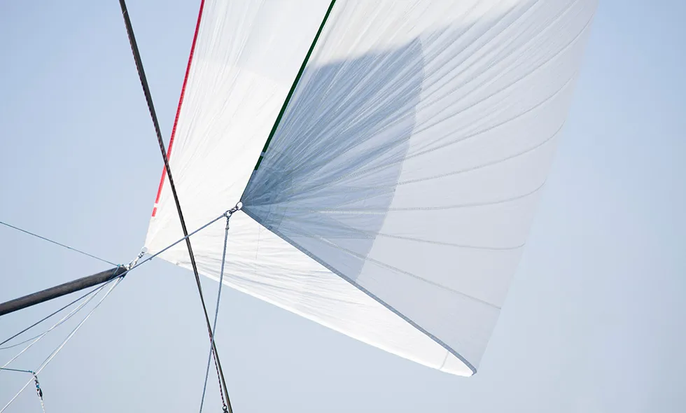Spinnakersegel på en båt som fångar vinden under klarblå himmel.