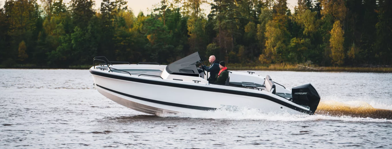 Motorbåt av tillverkaren Ryds färdas snabbt på en sjö omgiven av skog i bakgrunden.