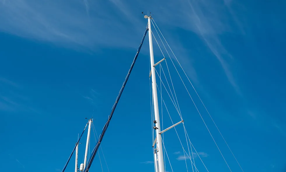 Masterna på en segelbåt mot en klarblå himmel.