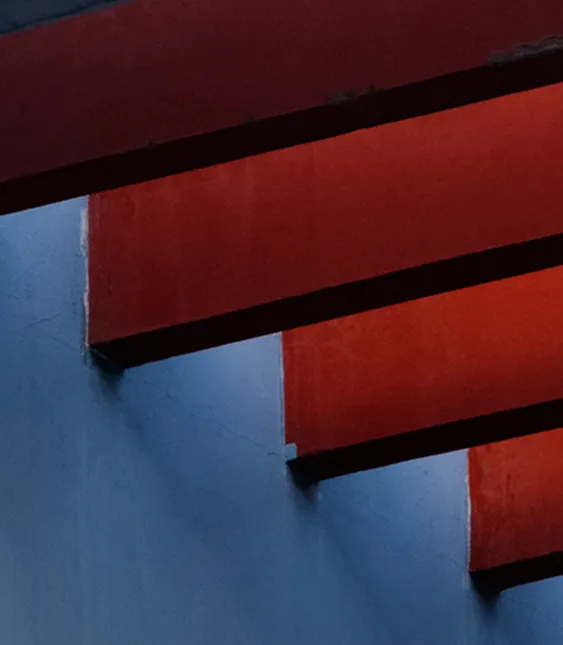 En abstrakt bild av röda trappsteg mot en blå vägg. Kontrasten mellan de två färgerna skapar ett iögonfallande mönster